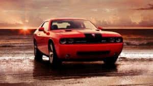 red dodge challenger parked on the beach