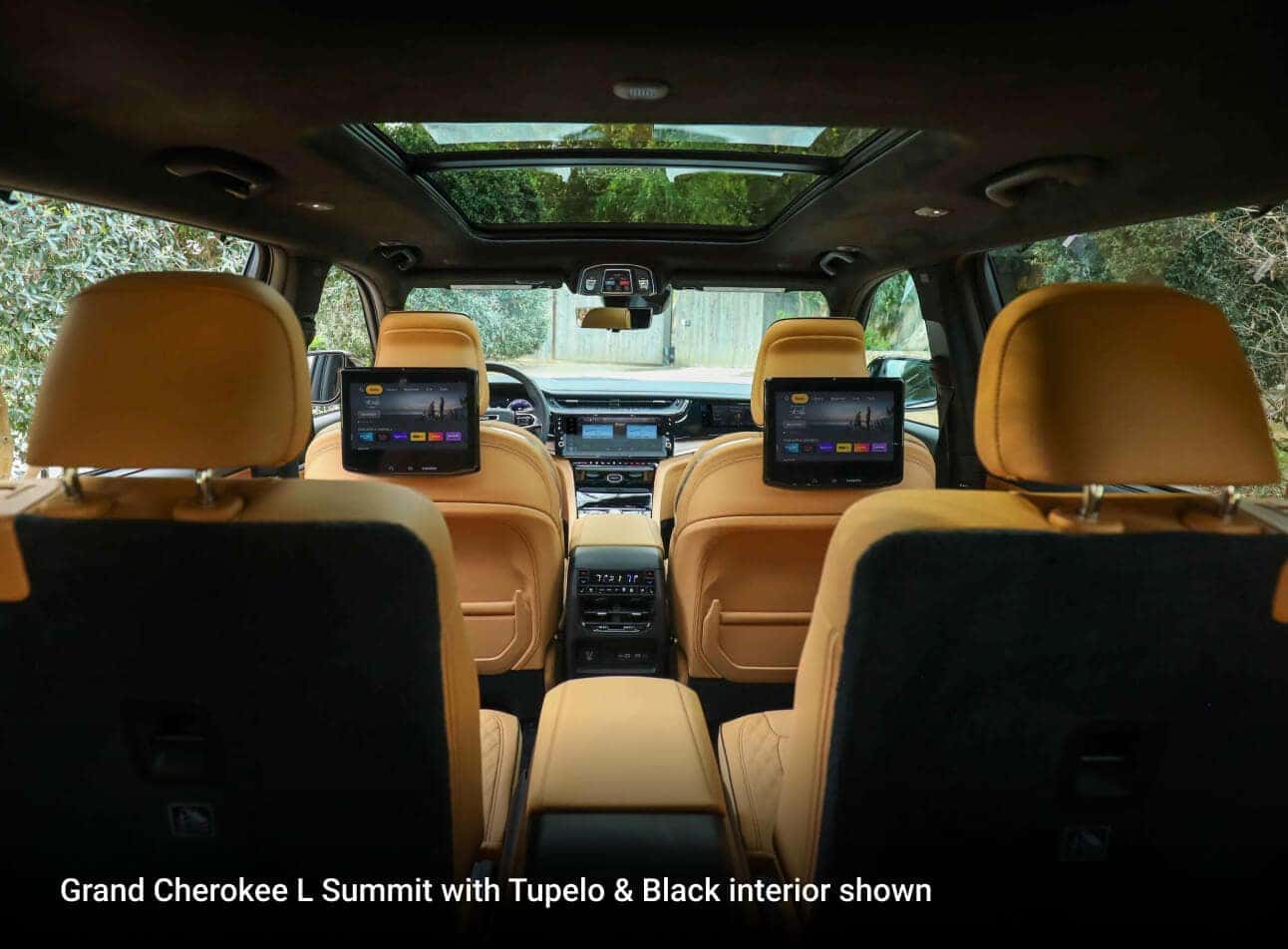 2026 Jeep Grand Cherokee L Summit with Tupelo & Black interior, rear cabin view with dual screens and panoramic roof.