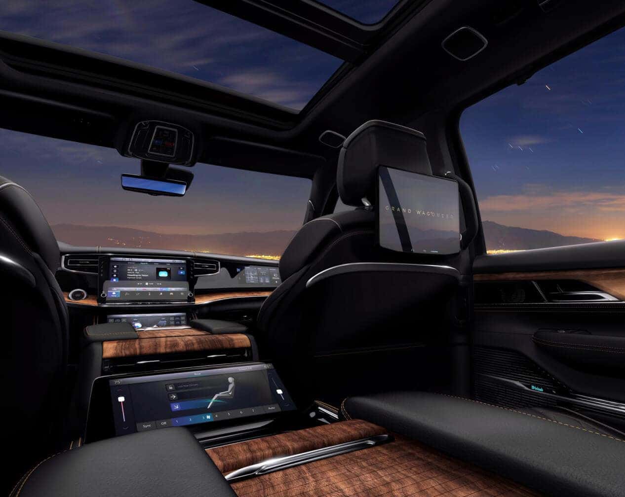 Rear interior view of a Jeep Grand Wagoneer in Global Black facing a sunset skyline.