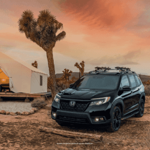 Front exterior view of the 2021 Honda Passport in black, surrounded by desert-located house and vegetation