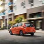 An orange 2019 Honda Fit drives down a city street during the day time