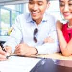 Couple signing sales contract for car at dealership