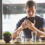 Man looks at tablet with espresso and water in coffee shop