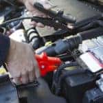 Close-Up Of Mechanic Attaching Jumper Cables To Car Battery