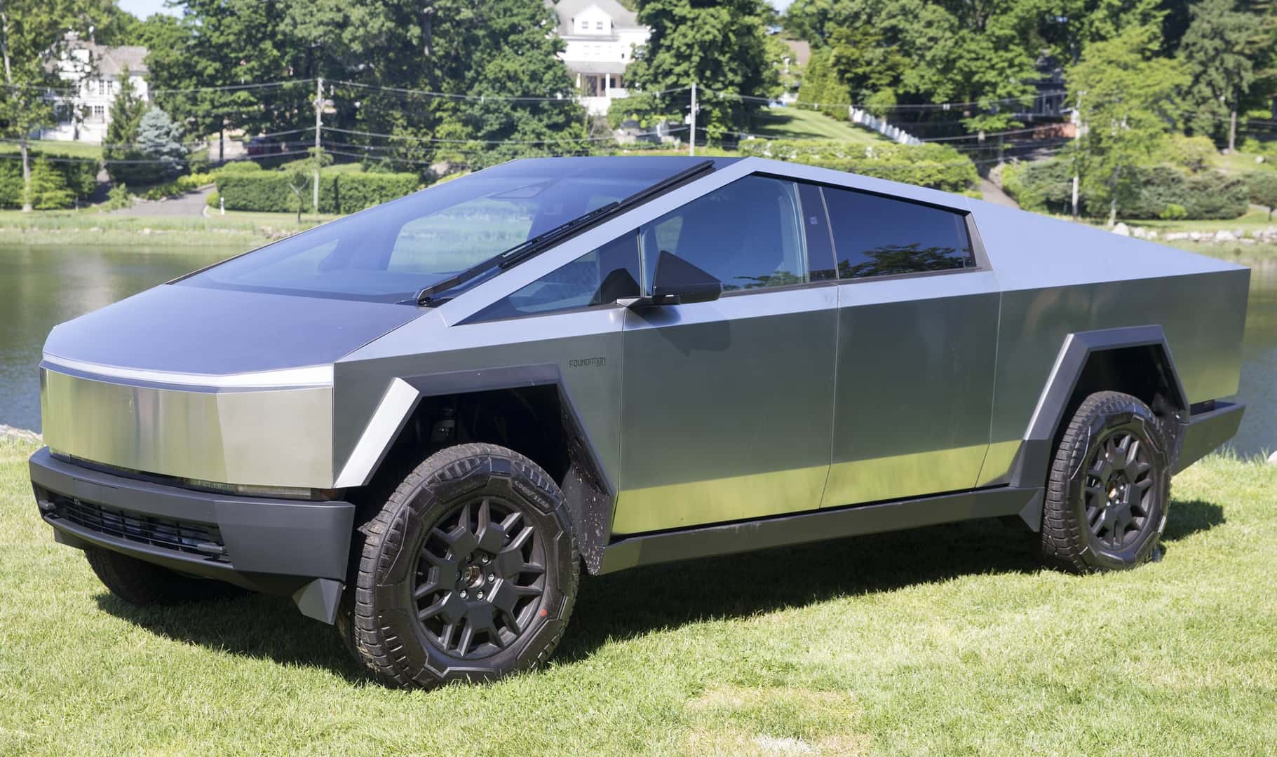 Stainless-steel 2024 Tesla Cybertruck Foundation Series viewed from the front and side on grass