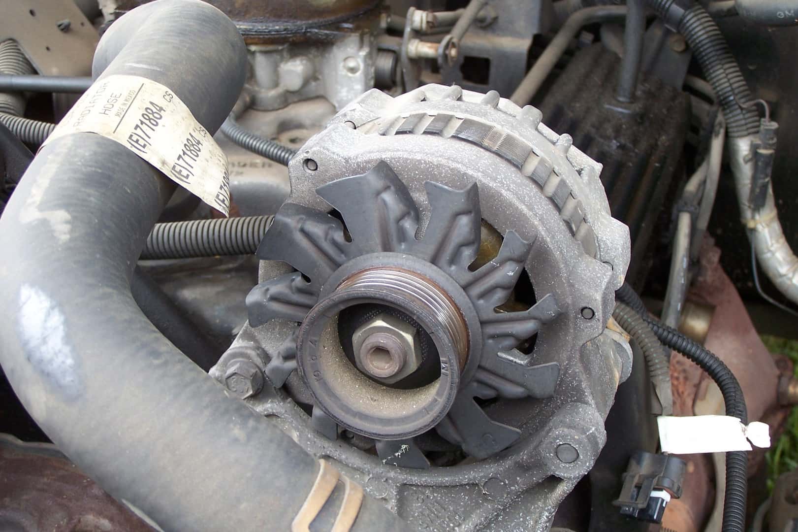 Alternator with a vented housing and grooved drive pulley in a vehicle engine bay