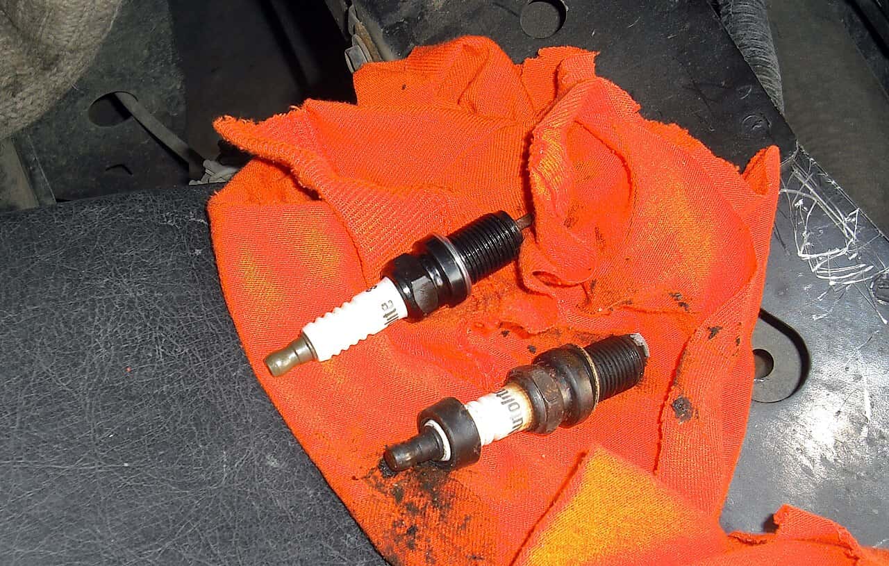 Two spark plugs lying diagonally on an orange cloth.