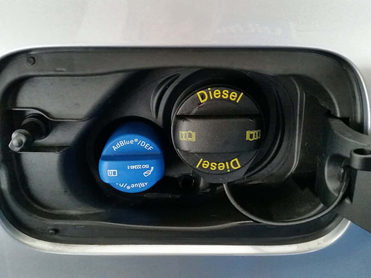 Blue AdBlue/DEF cap beside a black diesel cap in an Audi A4 B9 filler compartment.