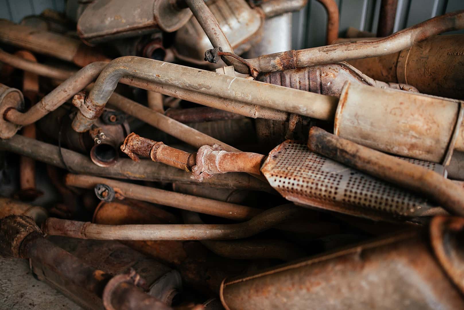 Removed exhaust pipes and mufflers with rusted surfaces, joints and hangers