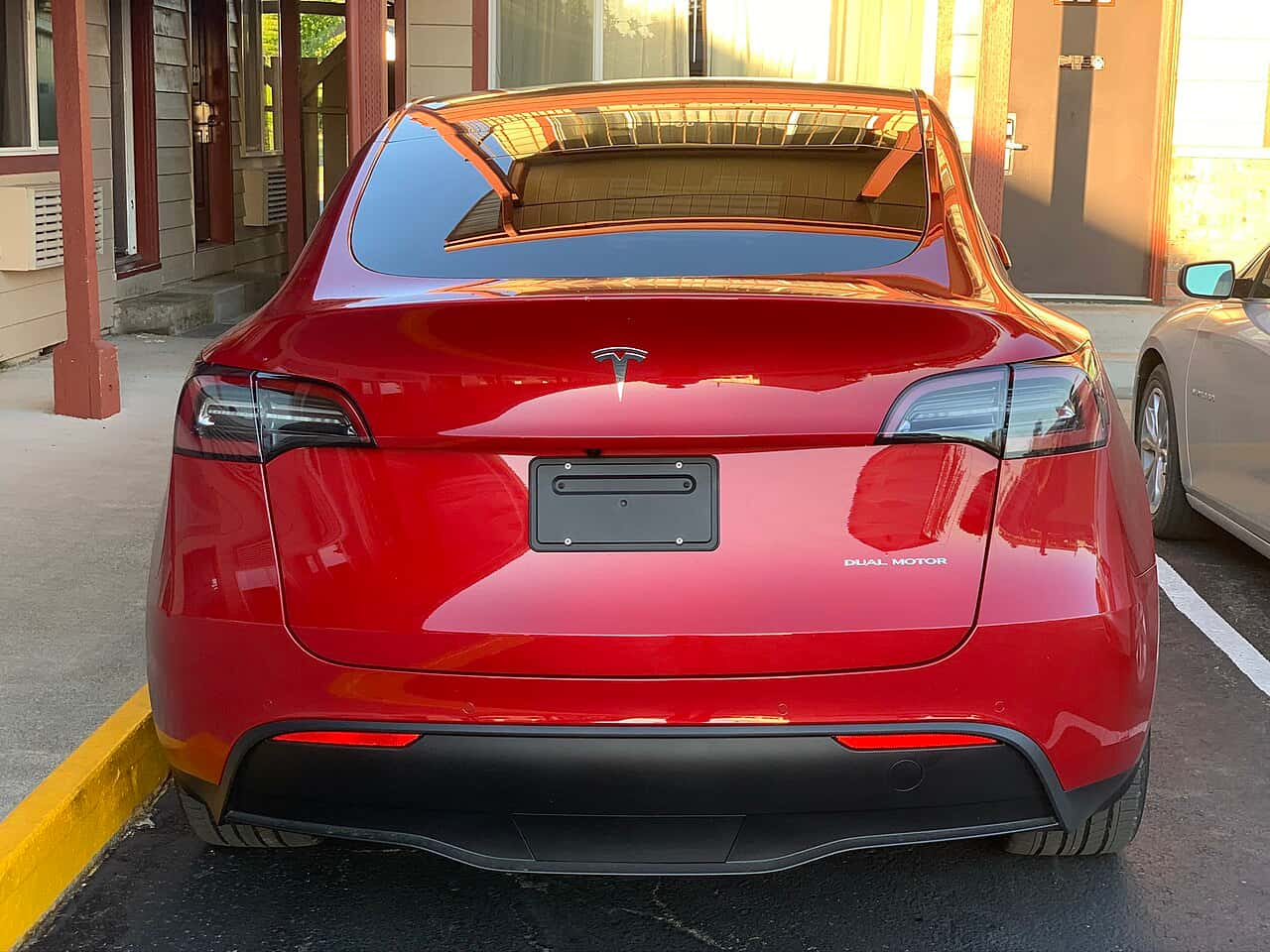 Rear view of a red Tesla Model Y parked beside a building