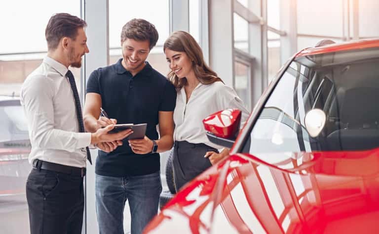 Couple reviewing vehicle purchase paperwork with a salesperson