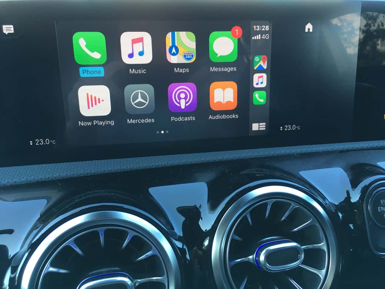 Real CarPlay app screen showing Phone, Music, Maps, Messages, Podcasts and Audiobooks above vehicle air vents