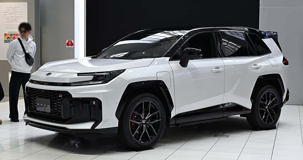 White 2026 Toyota RAV4 PHEV GR Sport prototype shown from the front three-quarter angle at a display.