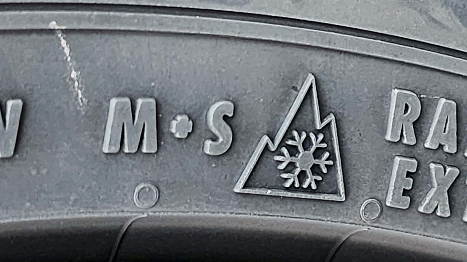 Close-up reference photograph of M+S lettering beside the three-peak mountain snowflake mark on a tire sidewall.