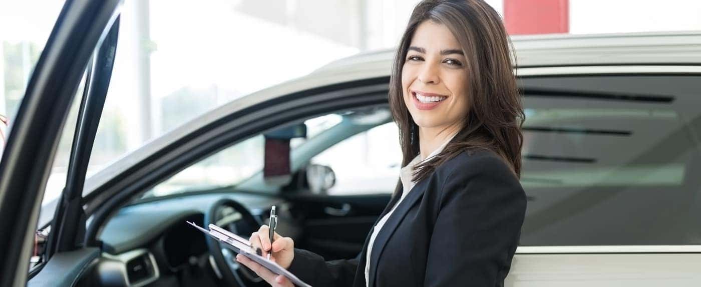 Saleswoman with car and clipboard