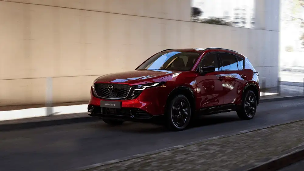 2026 Mazda CX-5 driving on city road with sleek red exterior near Hempstead NY