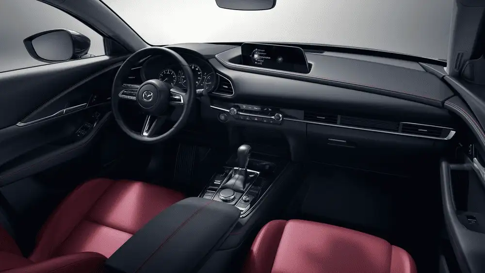2026 Mazda CX-30 near Uniondale NY interior dashboard view with red and black leather seats, Mazda infotainment screen, and rotary gear selector