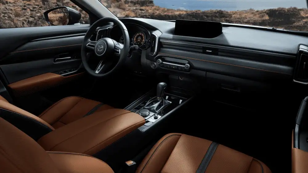 2026 Mazda CX-50 near Uniondale NY cockpit interior with tan leather seats, widescreen infotainment display, and panoramic view of rocky coastline