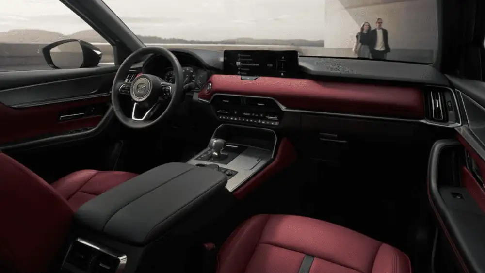 2026 Mazda CX-70 near Uniondale NY interior with red leather seats and dashboard trim, Mazda infotainment screen, and panoramic windows overlooking a lakeside terrace