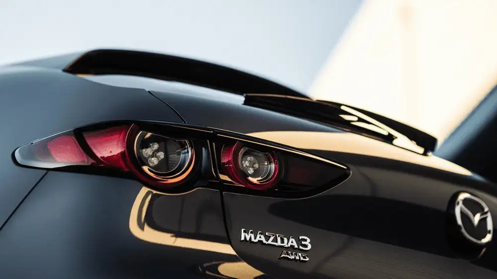 2026 Mazda3 Sedan near Uniondale NY close-up of dual circular LED taillights, rear spoiler, and Mazda3 AWD badge on jet black body