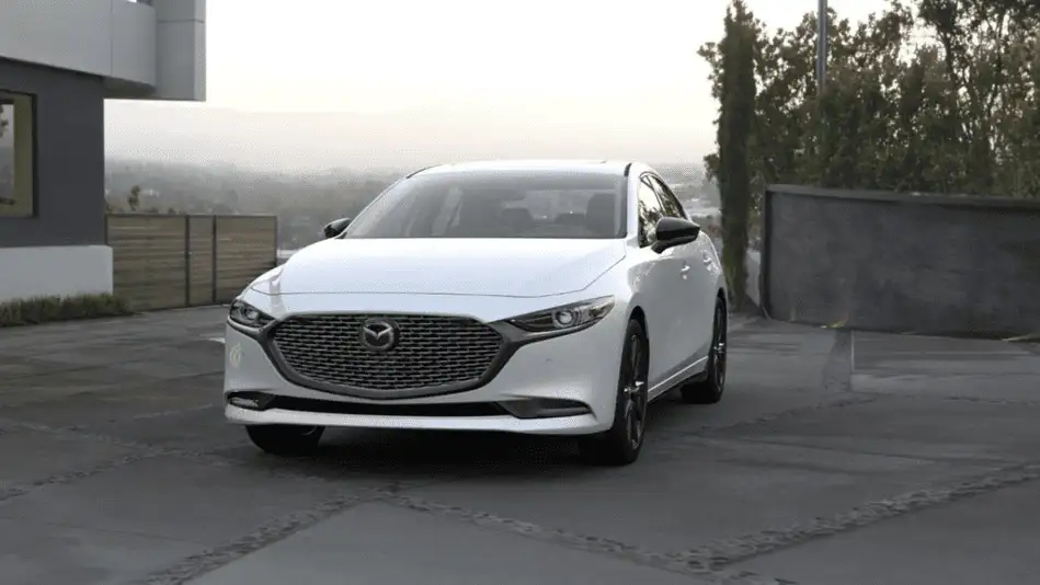 2026 Mazda3 Sedan out to Corona NY in Queens in white parked on rooftop lot facing forward with hazy city skyline and trees in background