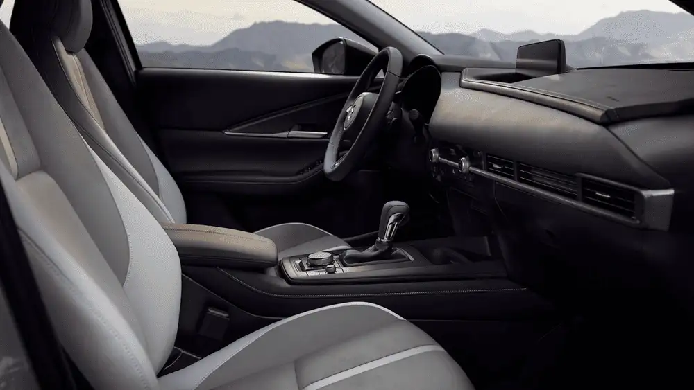2026 Mazda CX-30 close to Uniondale NY interior with light gray leather seats, black dashboard and center console, and mountain range visible through side windows