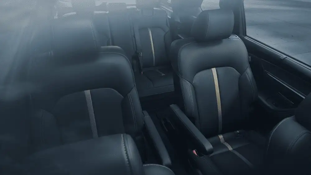 2026 Mazda CX-90 Plug-In Hybrid close to Uniondale NY full interior view showing three rows of black leather seats with gold accent trim in misty atmospheric lighting
