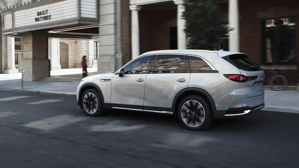 2026 Mazda CX-90 close to Uniondale NY interior dashboard with light gray leather seats, wide infotainment display, and sunlit suburban street visible through windshield