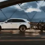 2026 Mazda CX-90 Plug-In Hybrid near Uniondale NY, white SUV towing a motorcycle trailer across a bridge