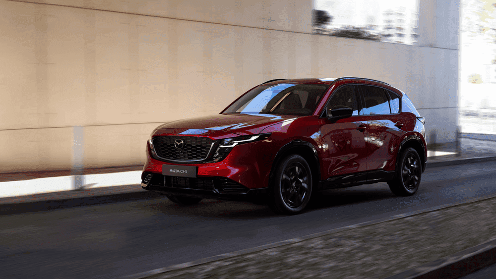 2026 Mazda CX-5 near Hempstead NY, red SUV with black wheels driving under an urban overpass