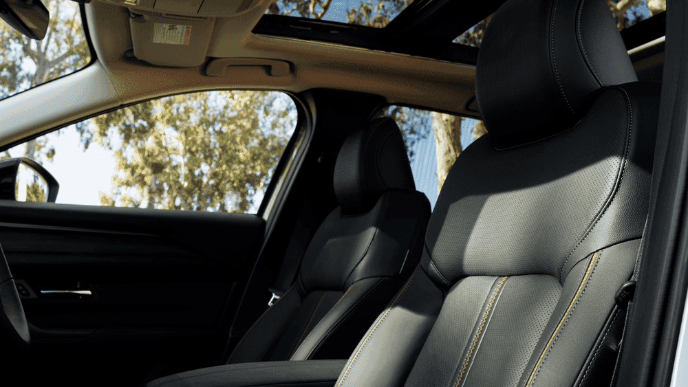 2026 Mazda CX-50 Hybrid near Hempstead NY, black leather front seats with gold accent stitching, open sunroof, and trees visible through side window