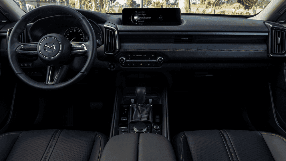 2026 Mazda CX-50 Hybrid near Hempstead NY, black interior dashboard with Mazda steering wheel, infotainment screen showing communication menu, and automatic gear selector