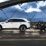 2026 Mazda CX-90 near Hempstead NY, white SUV towing a motorcycle trailer across a bridge at dusk