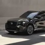 2026 Mazda CX-70 near Hempstead NY, jet black SUV driving through a sunlit modern parking structure