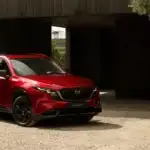 2026 Mazda CX-5 in red parked outside a modern building near Uniondale, NY, vs. Honda CR-V.