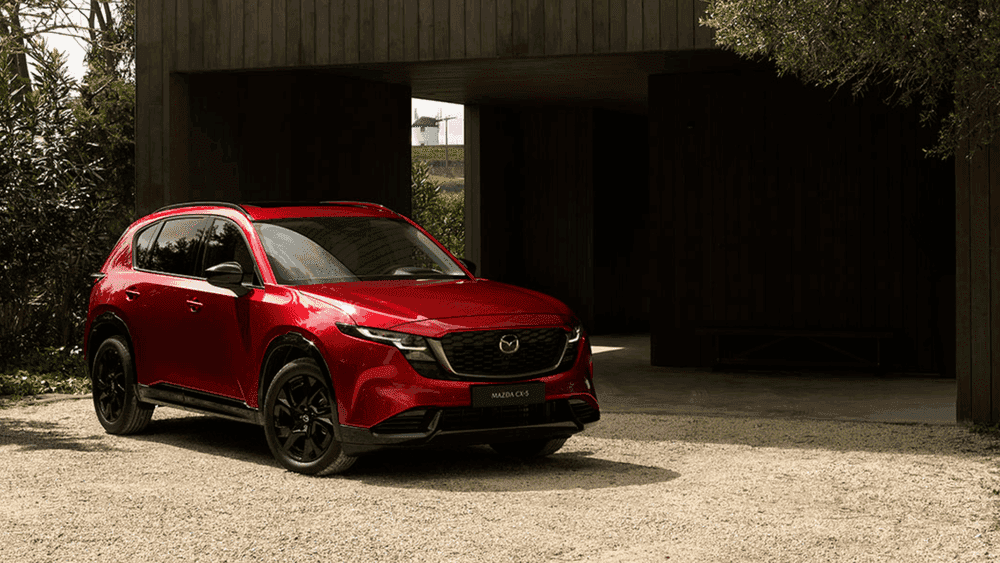 2026 Mazda CX-5 in red parked near a modern wood building, available near Uniondale, NY.