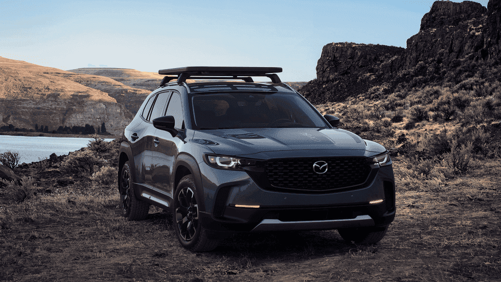 2026 Mazda CX-50 in gray with roof rack parked on desert terrain near Uniondale, NY.