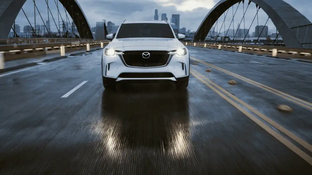 2026 Mazda CX-90 Plug-In Hybrid in white crossing a bridge near Uniondale, NY, vs. Volvo XC90 Recharge.
