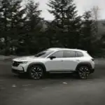 2026 Mazda CX-50 Hybrid in white driving through a forest road near Uniondale, NY.