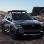 2026 Mazda CX-50 in gray with roof rack on rugged terrain near Uniondale, NY.
