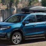 Blue Honda Pilot parked in front a lake with kayak on roof rack