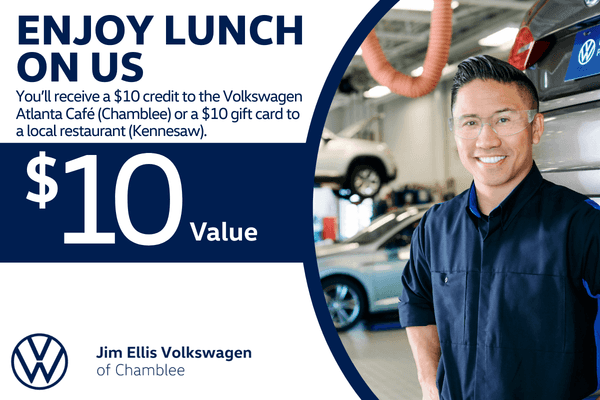 Volkswagen technician standing in a dealership service bay with vehicles in the background. Graphic advertises a $10 lunch credit at Volkswagen Atlanta Café in Chamblee or a $10 gift card to a local restaurant during a service visit at Jim Ellis Volkswagen of Chamblee.
