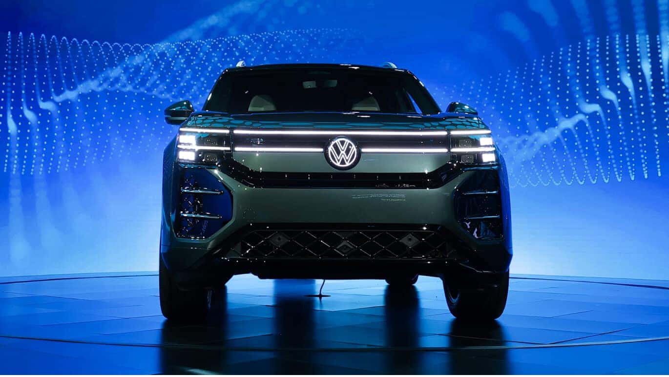 Sacramento Green 2027 Volkswagen Atlas SEL Premium R-Line front view on a rotating auto show stage.
