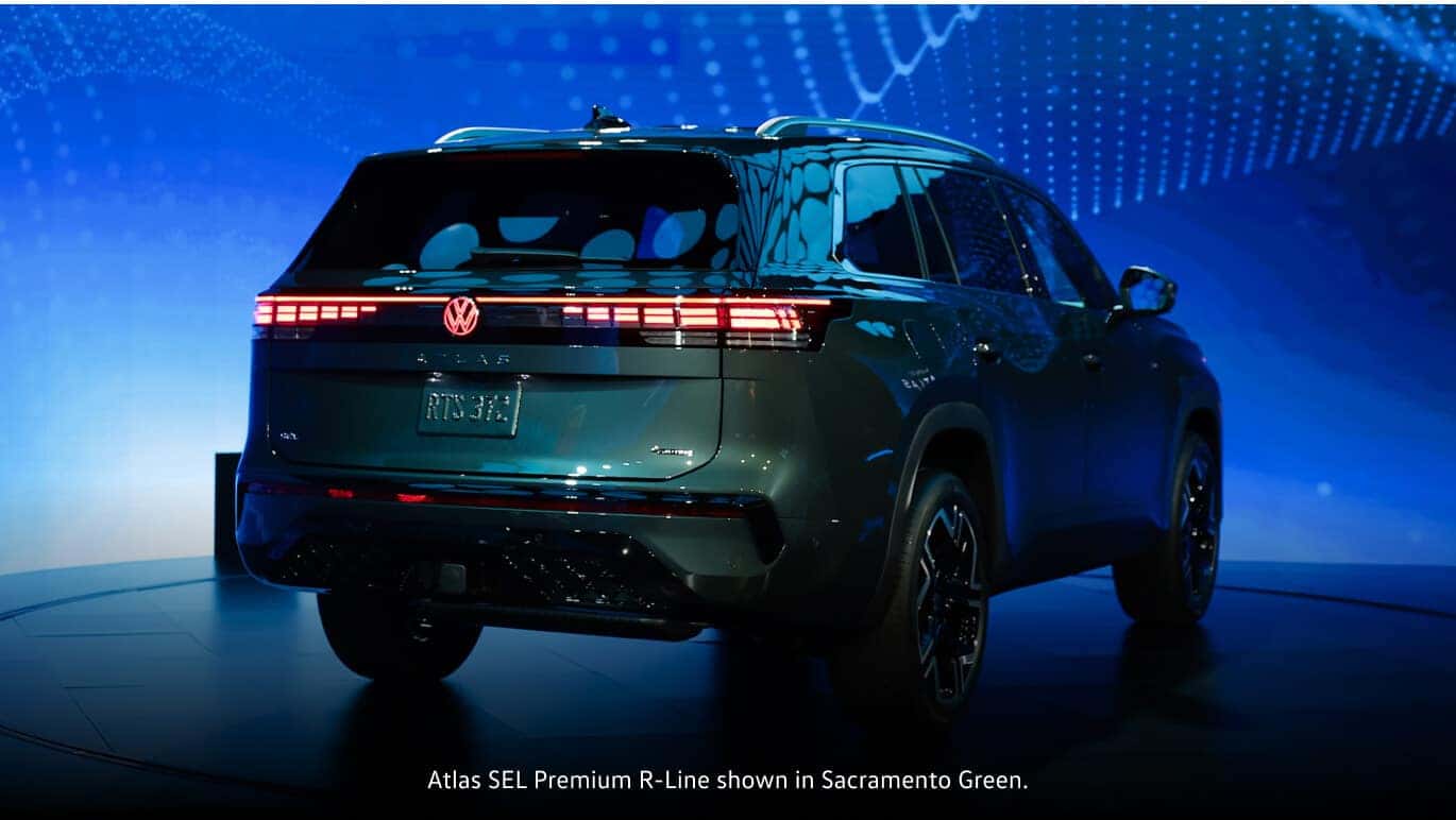 Sacramento Green 2027 Volkswagen Atlas SEL Premium R-Line rear view on a rotating auto show stage.