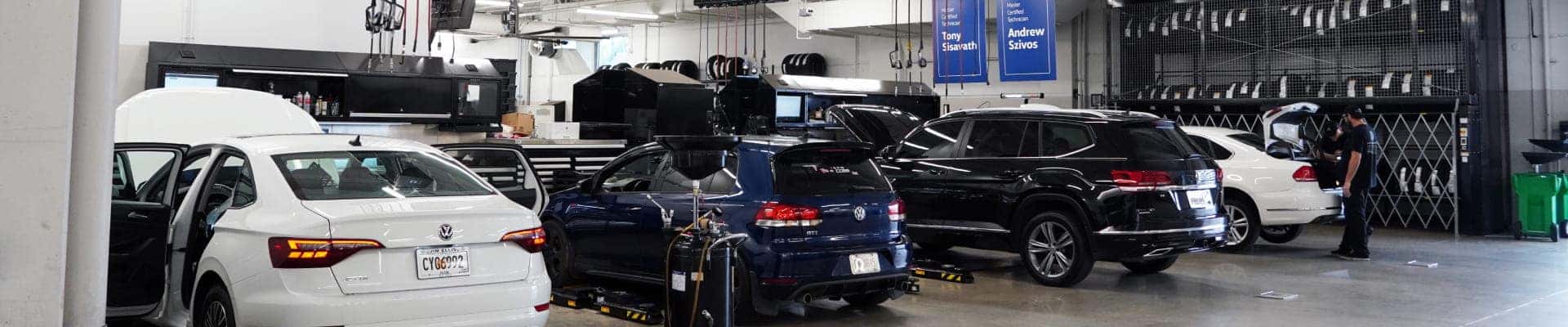 Volkswagen vehicles being serviced inside an automotive service center.