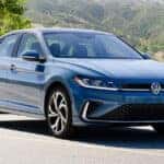 2026 Volkswagen Jetta sedan parked on a scenic road with trees and mountains.