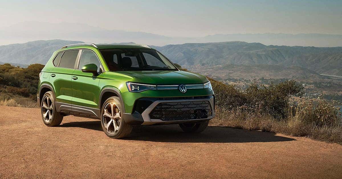 2027 Volkswagen Taos SUV driving on a scenic mountain road in a green exterior.
