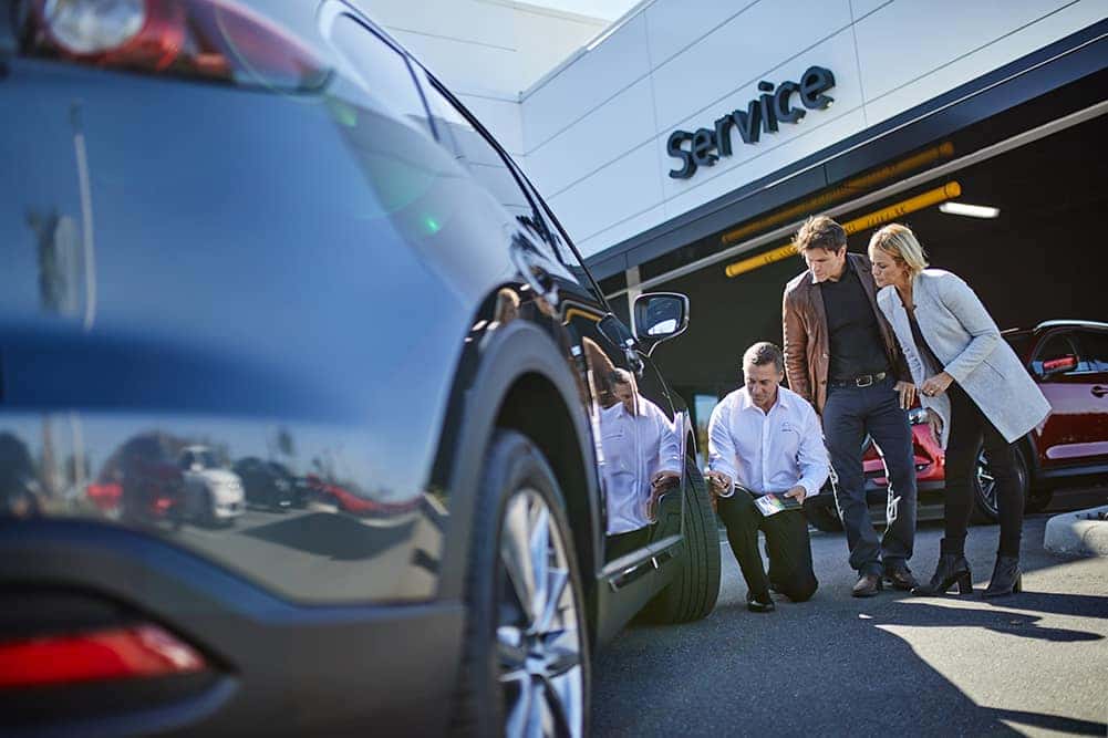 How to check your tires' health at Lancaster Mazda | Mazda salesman checking tire pressure for customers