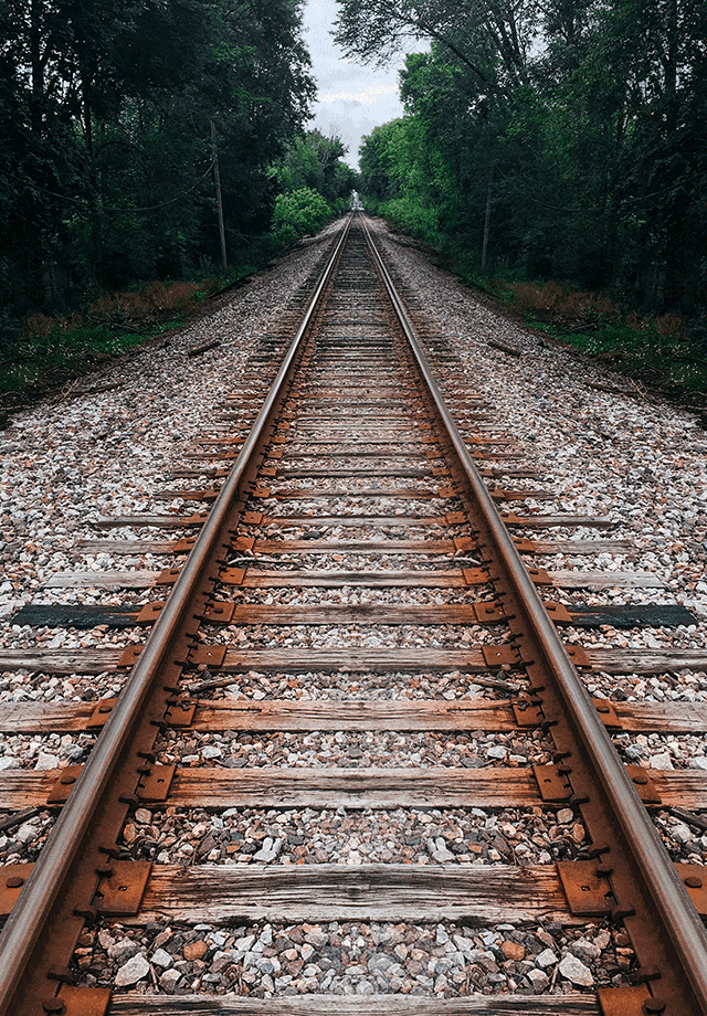 Lancaster Mazda is a Mazda Dealership near Reading, PA | Low Angle Shot in Center of Railroad Tracks Leading Eyes Down the Track into Forest