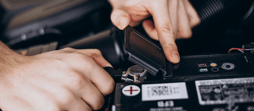 Everything You Need to Know about Your Car Battery at Lancaster Mazda | Person's hnad lifting battery cover to check if the battery is not leaking